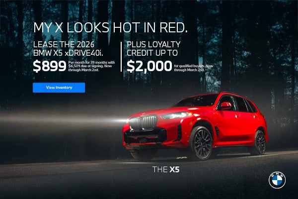 2026 BMW X5 driving through dark woodland.